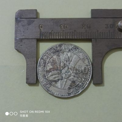 这枚硬币经历了什么？😂
战损版危地马拉硬币 2007年50分
危地马拉的硬币辨识度也很高，因为这个国徽相对来说真的很独特，象征自由的国鸟格查尔鸟站在卷轴上，卷轴上的字是1821年9月15日自由，然后卷轴是架在两把刀两把上了刺刀的枪上的。
危地马拉有多喜欢格查尔鸟？货币主币就叫格查尔，100分=1格查尔，👍🏻
图案是危地马拉国花白兰花。