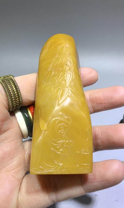田黄石线雕印章
一两田黄十两金，市面上有“石帝”印石之王的美称。打灯肌理表皮组织可见密如之网的细萝卜纹，条理清晰。表皮可见一处天然裂格。博弈工，收藏级。尺寸:7.2cm*2.7cm克重:100.4g