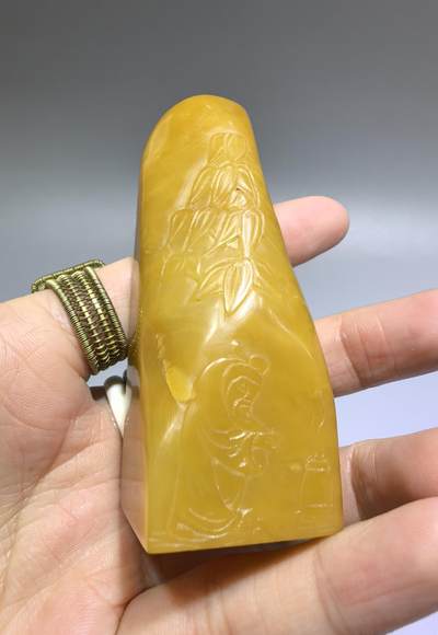 田黄石线雕印章
一两田黄十两金，市面上有“石帝”印石之王的美称。打灯肌理表皮组织可见密如之网的细萝卜纹，条理清晰。表皮可见一处天然裂格。博弈工，收藏级。尺寸:7.2cm*2.7cm克重:100.4g