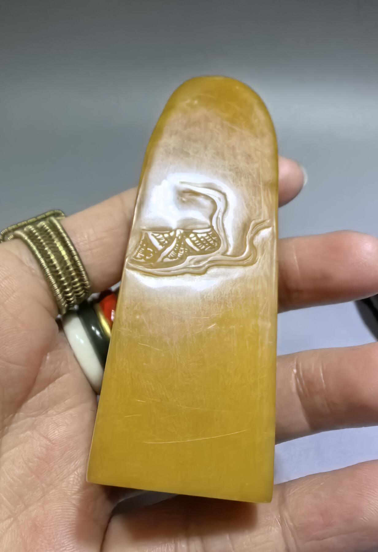 田黄石线雕印章
一两田黄十两金，市面上有“石帝”印石之王的美称。打灯肌理表皮组织可见密如之网的细萝卜纹，条理清晰。表皮可见一处天然裂格。博弈工，收藏级。尺寸:7.2cm*2.7cm克重:100.4g