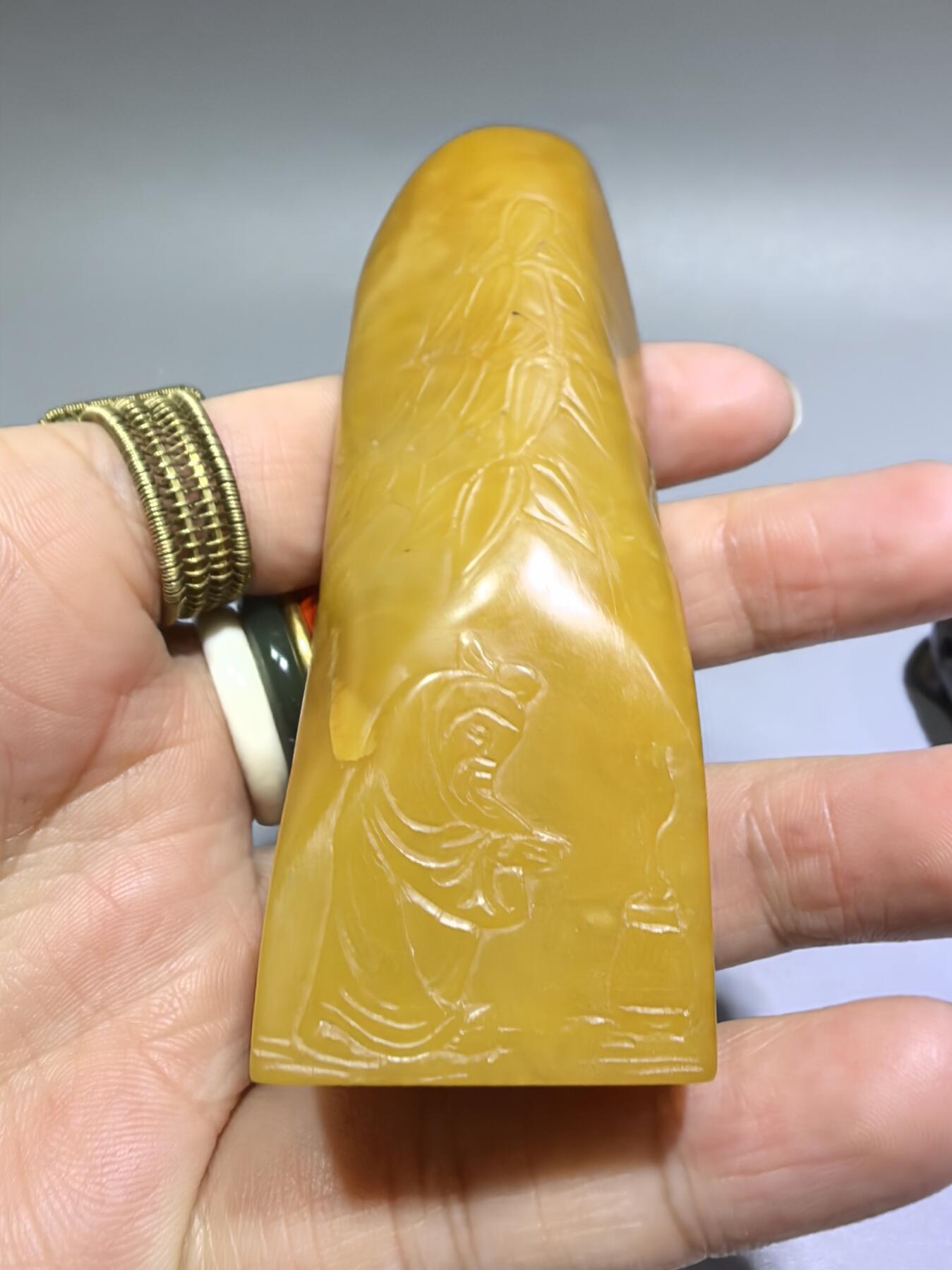 田黄石线雕印章
一两田黄十两金，市面上有“石帝”印石之王的美称。打灯肌理表皮组织可见密如之网的细萝卜纹，条理清晰。表皮可见一处天然裂格。博弈工，收藏级。尺寸:7.2cm*2.7cm克重:100.4g