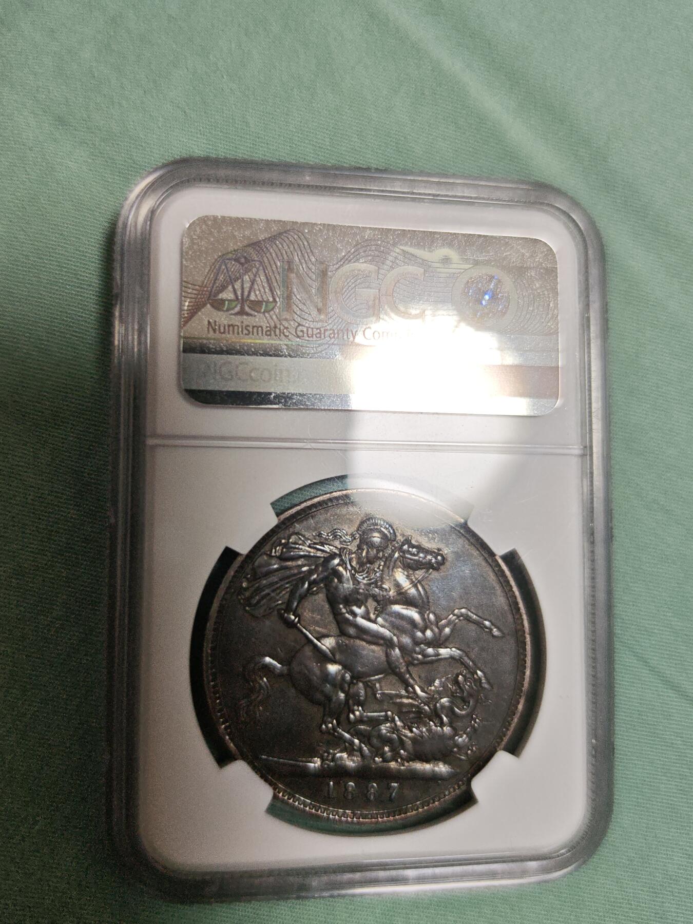 NGC AU53 黑丝入骨传世重黑油酱彩极品品相，大英帝国维多利亚女王高皇冠圣乔治骑士屠龙马剑大银元。状态极佳，字口全深打，人物细节拉满，气势十足，底板清爽干净，传世老黑油包浆醇熟入骨，明显低评压分的一枚大马剑老银元