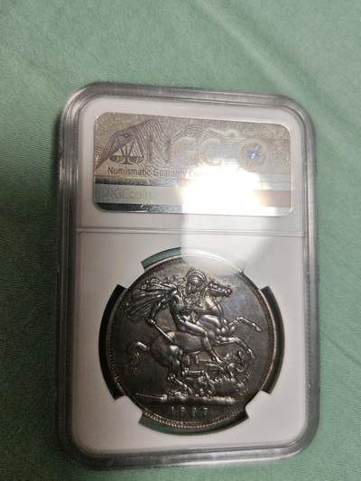 NGC AU53 黑丝入骨传世重黑油酱彩极品品相，大英帝国维多利亚女王高皇冠圣乔治骑士屠龙马剑大银元。状态极佳，字口全深打，人物细节拉满，气势十足，底板清爽干净，传世老黑油包浆醇熟入骨，明显低评压分的一枚大马剑老银元