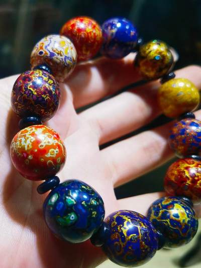 非遗大漆满螺钿手串鼓珠，甄选天然材质，匠心工艺，它是一种树脂涂料，生长条件严苛，成熟缓慢，漆树需生长10年才能割采，一颗漆树整个生命周期只能割出10公斤生漆，3000颗漆树采集一公斤生漆，有“百里千刀一斤漆”的说法，收集完后过滤提取成为优良大漆，它耐酸、耐潮、耐高温，天然环保。大漆工艺是一种表面涂漆，并以彩绘，雕刻加以美化，利用不同的色彩，不同的空间对比以及映照营造出立体的视觉美感的手工艺术。