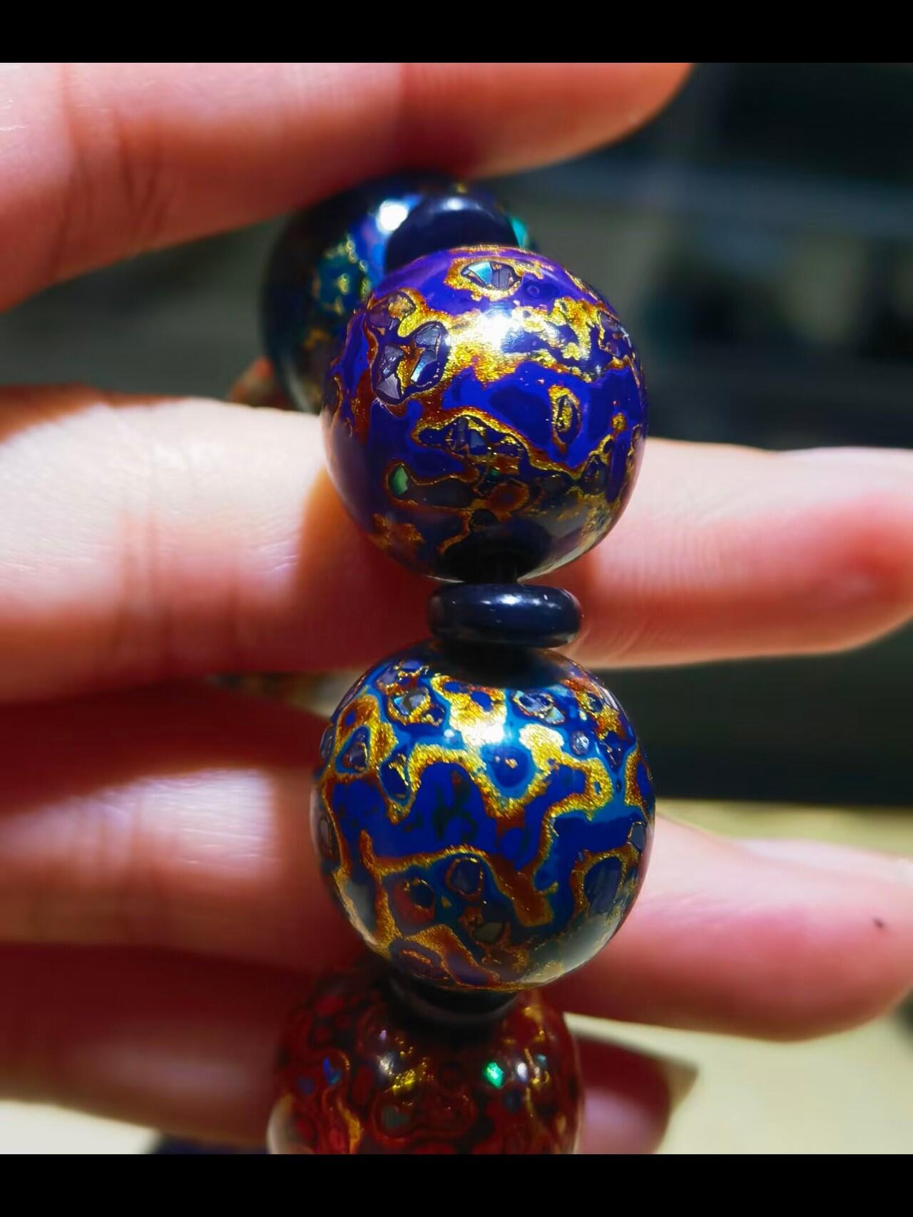 非遗大漆满螺钿手串鼓珠，甄选天然材质，匠心工艺，它是一种树脂涂料，生长条件严苛，成熟缓慢，漆树需生长10年才能割采，一颗漆树整个生命周期只能割出10公斤生漆，3000颗漆树采集一公斤生漆，有“百里千刀一斤漆”的说法，收集完后过滤提取成为优良大漆，它耐酸、耐潮、耐高温，天然环保。大漆工艺是一种表面涂漆，并以彩绘，雕刻加以美化，利用不同的色彩，不同的空间对比以及映照营造出立体的视觉美感的手工艺术。