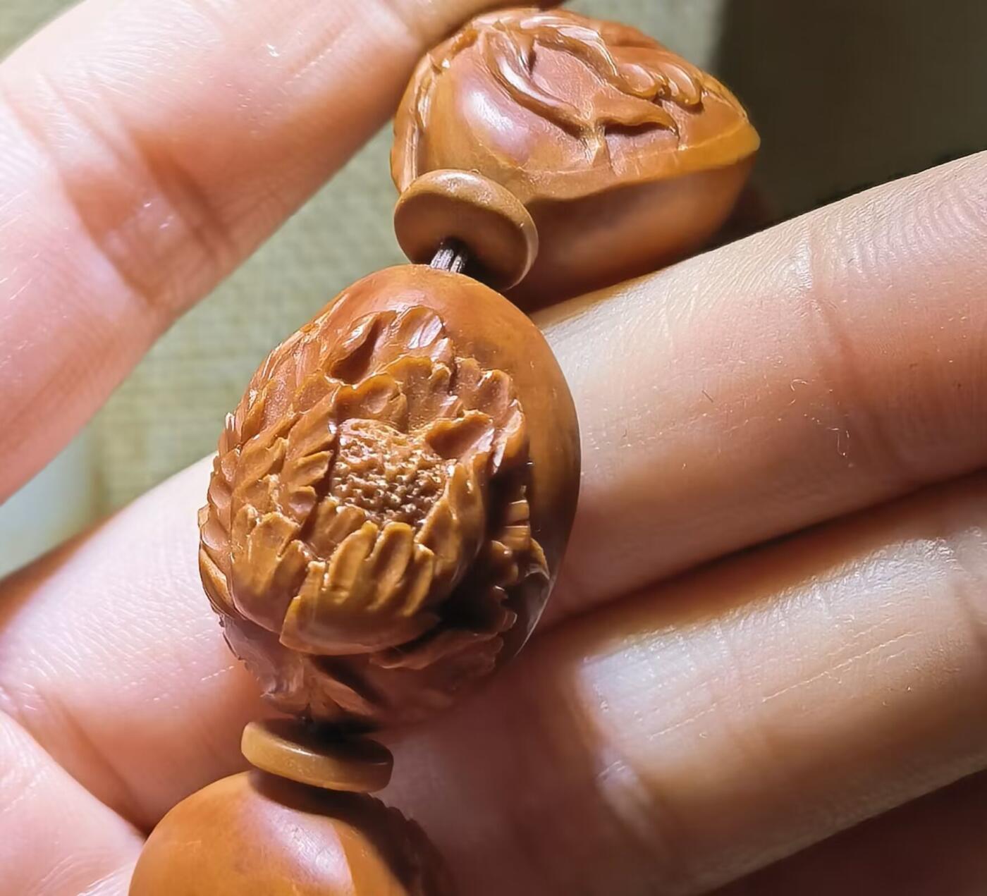 纯手工橄榄核浮雕凤穿牡丹男款手串佛珠，三花扁核浮雕凤穿牡丹花瓣雕刻栩栩如生，花瓣花蕊清晰渐层，扁核需要在不同面连贯雕刻，考验雕刻师的雕刻技术可见清晰留刀痕尺寸：18宽mm*24长mm