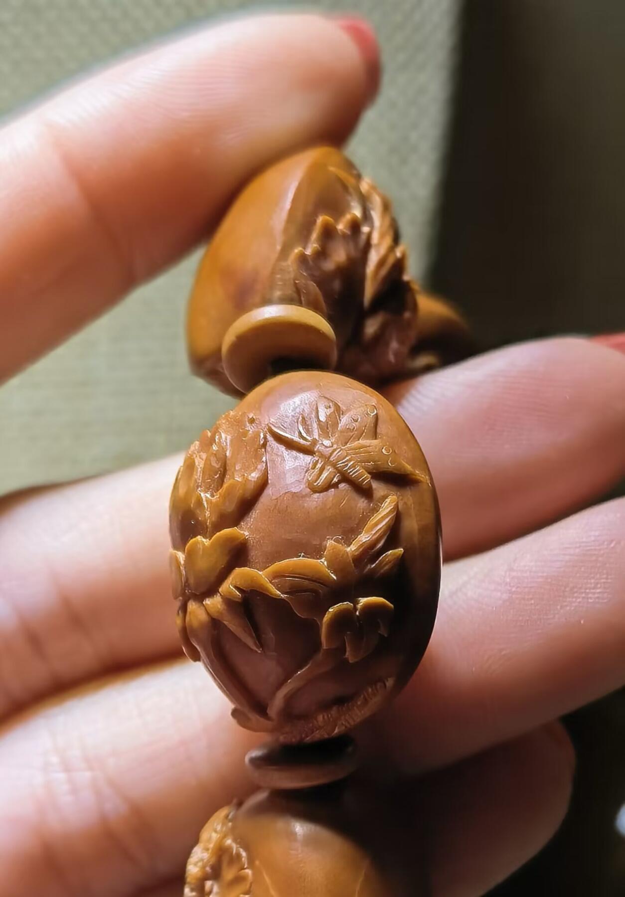 纯手工橄榄核浮雕凤穿牡丹男款手串佛珠，三花扁核浮雕凤穿牡丹花瓣雕刻栩栩如生，花瓣花蕊清晰渐层，扁核需要在不同面连贯雕刻，考验雕刻师的雕刻技术可见清晰留刀痕尺寸：18宽mm*24长mm