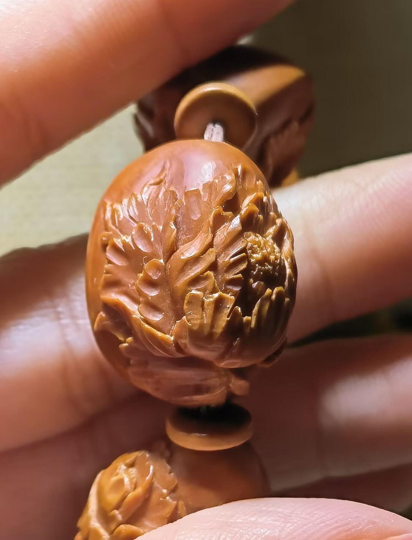 纯手工橄榄核浮雕凤穿牡丹男款手串佛珠，三花扁核浮雕凤穿牡丹花瓣雕刻栩栩如生，花瓣花蕊清晰渐层，扁核需要在不同面连贯雕刻，考验雕刻师的雕刻技术可见清晰留刀痕尺寸：18宽mm*24长mm