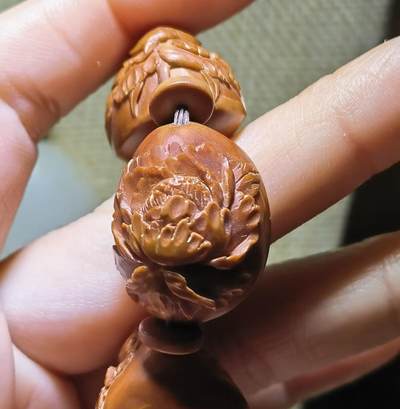 纯手工橄榄核浮雕凤穿牡丹男款手串佛珠，三花扁核浮雕凤穿牡丹花瓣雕刻栩栩如生，花瓣花蕊清晰渐层，扁核需要在不同面连贯雕刻，考验雕刻师的雕刻技术可见清晰留刀痕尺寸：18宽mm*24长mm