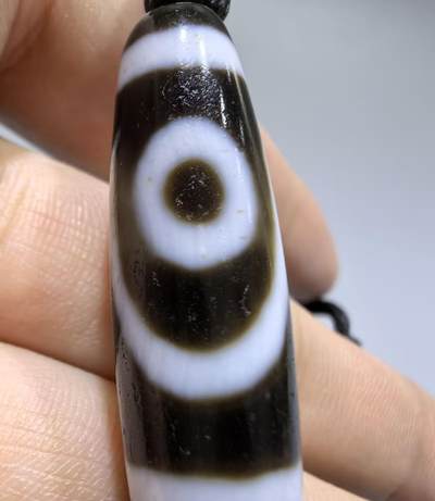 行运二眼天珠手链纯手工珠男女款手串
此款二眼天珠，是行运家早期品相，属于黑白品相，但是行运家天珠的特点就黑线部分远看是黑，上了倍镜以后是深褐色，珠体表面可见细风化纹，手工绘制图腾。
​尺寸:3.8*1.0cm
​