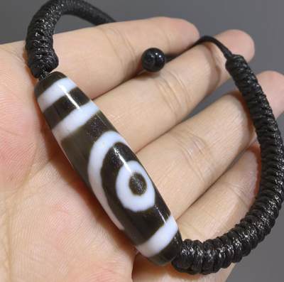 行运二眼天珠手链纯手工珠男女款手串
此款二眼天珠，是行运家早期品相，属于黑白品相，但是行运家天珠的特点就黑线部分远看是黑，上了倍镜以后是深褐色，珠体表面可见细风化纹，手工绘制图腾。
​尺寸:3.8*1.0cm
​