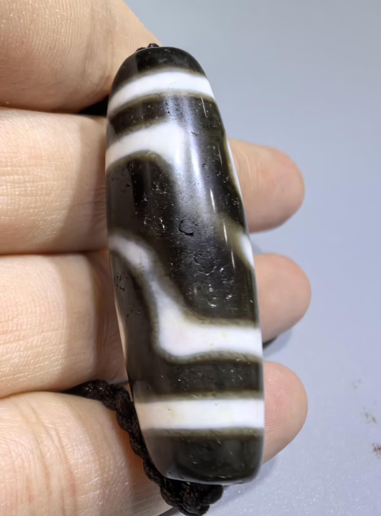 清末民国二眼天珠项链清末民国二眼天珠
此款二眼天珠是小年份大清至民国。可见明显的岁月包浆痕迹，珠体有明显的油沁，这是由于长时间佩戴，人体的油脂已经渗透到玛瑙里，产生了灰沁。
​尺寸:3.8*1.1cm
​