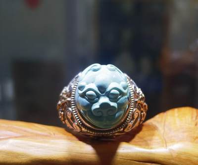 纯天然原矿松石雕刻兽面戒指男款，纯天然原矿松石能做雕刻要求瓷度密度比较高。松石瓷度不够，在雕刻的过程中容易松散，裸石干净漂亮。纯手工雕刻。霸气侧漏。尺寸:16mm×14mm*8mm纯银镂空镶嵌可调节指圈。