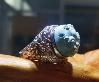 纯天然原矿松石雕刻兽面戒指男款，纯天然原矿松石能做雕刻要求瓷度密度比较高。松石瓷度不够，在雕刻的过程中容易松散，裸石干净漂亮。纯手工雕刻。霸气侧漏。尺寸:16mm×14mm*8mm纯银镂空镶嵌可调节指圈。