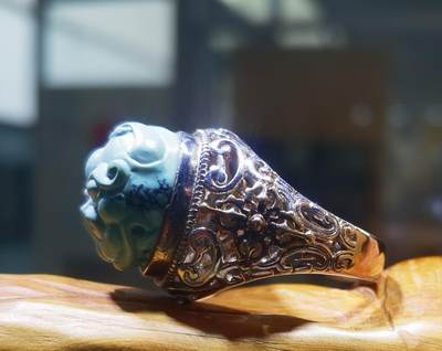 纯天然原矿松石雕刻兽面戒指男款，纯天然原矿松石能做雕刻要求瓷度密度比较高。松石瓷度不够，在雕刻的过程中容易松散，裸石干净漂亮。纯手工雕刻。霸气侧漏。尺寸:16mm×14mm*8mm纯银镂空镶嵌可调节指圈。