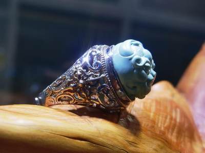 纯天然原矿松石雕刻兽面戒指男款，纯天然原矿松石能做雕刻要求瓷度密度比较高。松石瓷度不够，在雕刻的过程中容易松散，裸石干净漂亮。纯手工雕刻。霸气侧漏。尺寸:16mm×14mm*8mm纯银镂空镶嵌可调节指圈。