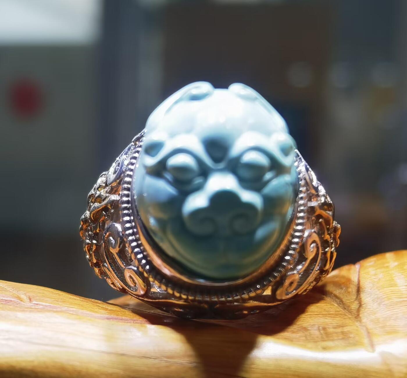 纯天然原矿松石雕刻兽面戒指男款，纯天然原矿松石能做雕刻要求瓷度密度比较高。松石瓷度不够，在雕刻的过程中容易松散，裸石干净漂亮。纯手工雕刻。霸气侧漏。尺寸:16mm×14mm*8mm纯银镂空镶嵌可调节指圈。
