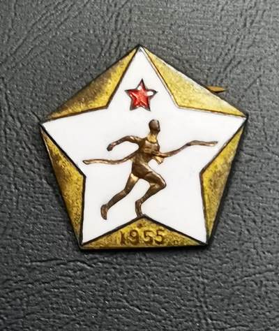 - 正面：五角星造型，珐琅工艺打造，白色底面上有金色跑步运动员浮雕，顶部缀红色五角星，下方刻有“1955”年份，整体设计融合了体育主题与时代符号。
​
- 背面：刻有“北京铁路管理局 体育积极分子”字样及编号“176”，明确了颁发单位、表彰类别与藏品的唯一性。
​
​
- 1950年代是新中国体育事业奠基期，铁路系统作为大型国企，积极开展职工体育活动，这类纪念章是对参与体育建设、推动全民健身职工的表彰。
​
- 北京铁道学院（今北京交通大学）作为铁路系统核心高校，同步推行体育育人理念，这类徽章也成为校园体育文化的重要载体。