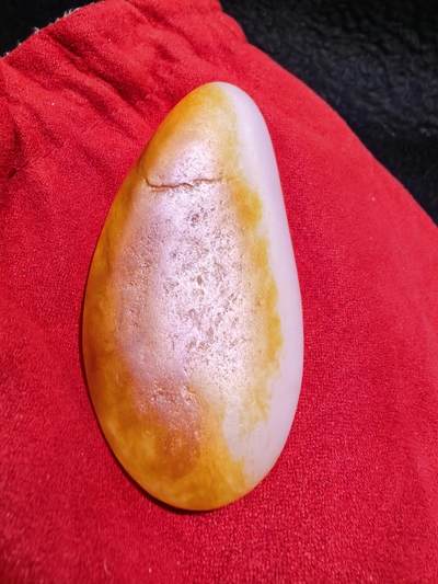 收藏级新疆和田籽料金红皮吊坠挂件手把件男款，原皮、原籽、无修、无烧皮、无做色、通体可见天然毛孔撞击坑等。玉质温润细腻，过灯无明显结构。细度高老熟，暖白不闪青，皮色鲜艳，亮气自然。未打孔。实物实拍，所见即所得。
尺寸:7.5cm*3.9cm*1.3cm
克重:68.5g