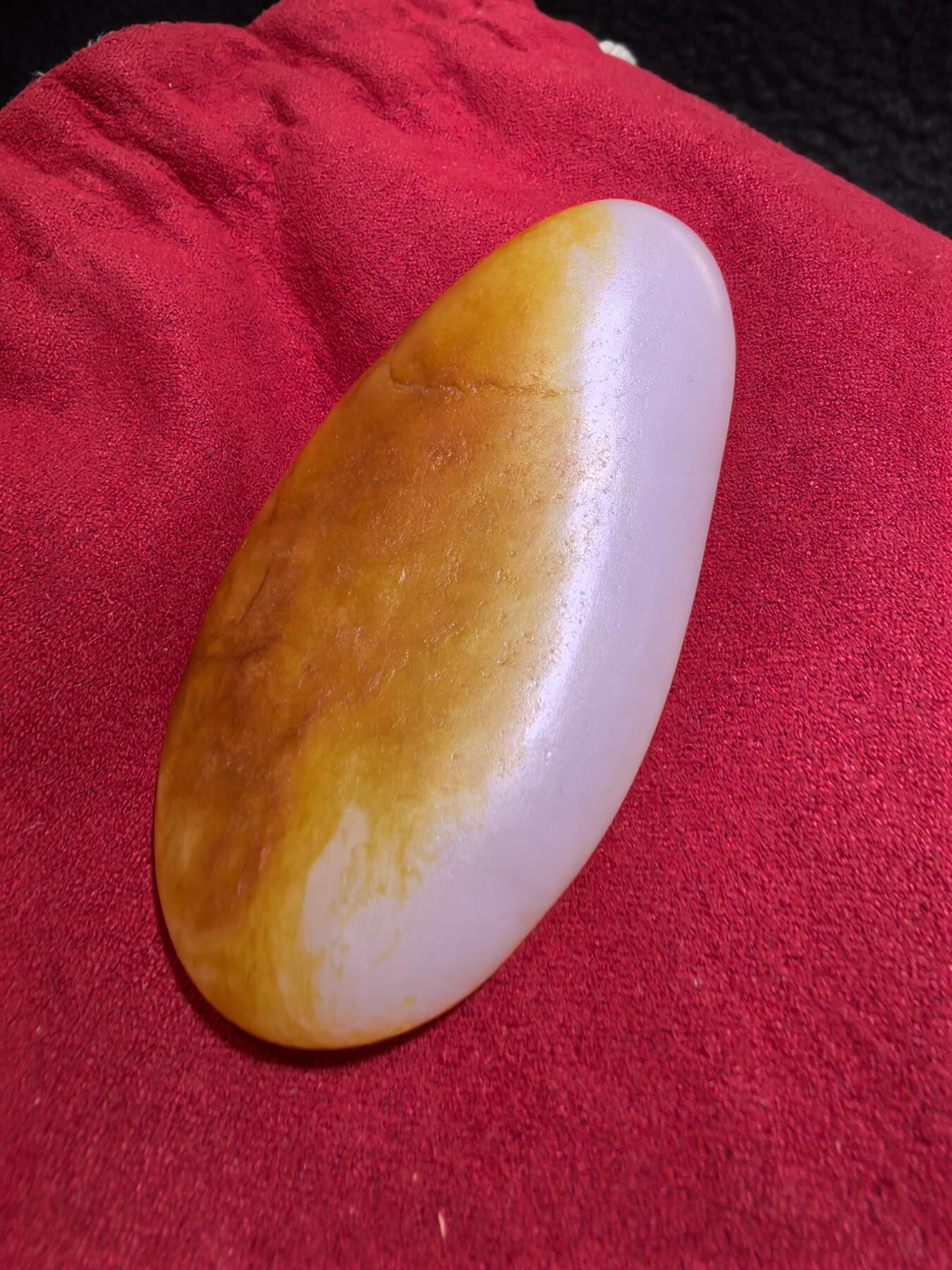 收藏级新疆和田籽料金红皮吊坠挂件手把件男款，原皮、原籽、无修、无烧皮、无做色、通体可见天然毛孔撞击坑等。玉质温润细腻，过灯无明显结构。细度高老熟，暖白不闪青，皮色鲜艳，亮气自然。未打孔。实物实拍，所见即所得。
尺寸:7.5cm*3.9cm*1.3cm
克重:68.5g