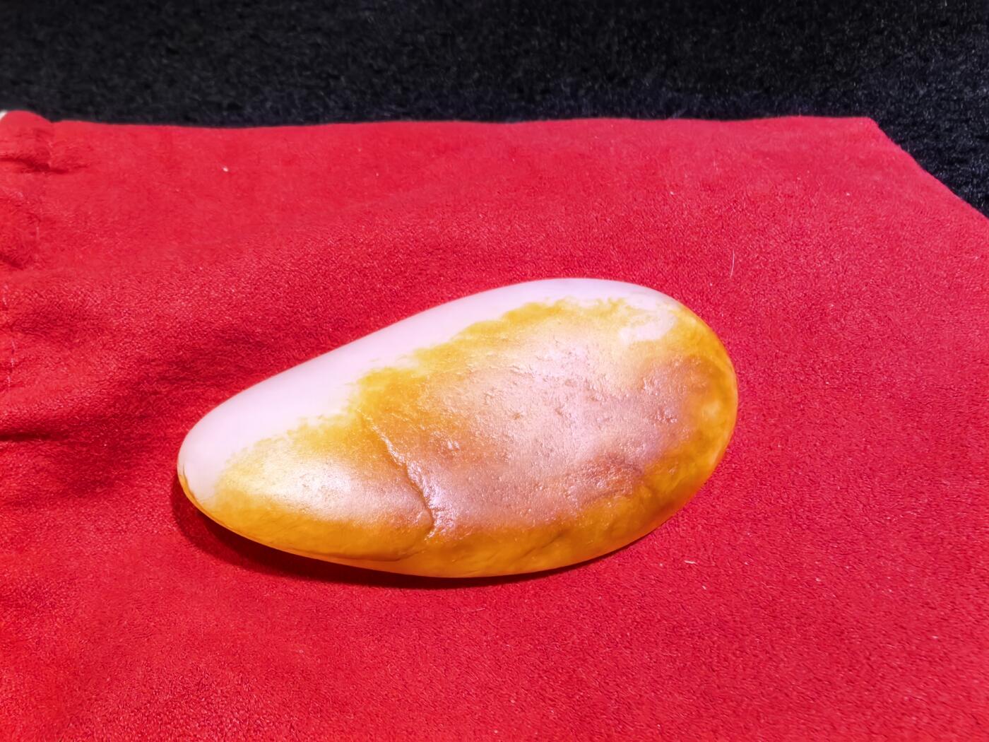 收藏级新疆和田籽料金红皮吊坠挂件手把件男款，原皮、原籽、无修、无烧皮、无做色、通体可见天然毛孔撞击坑等。玉质温润细腻，过灯无明显结构。细度高老熟，暖白不闪青，皮色鲜艳，亮气自然。未打孔。实物实拍，所见即所得。
尺寸:7.5cm*3.9cm*1.3cm
克重:68.5g