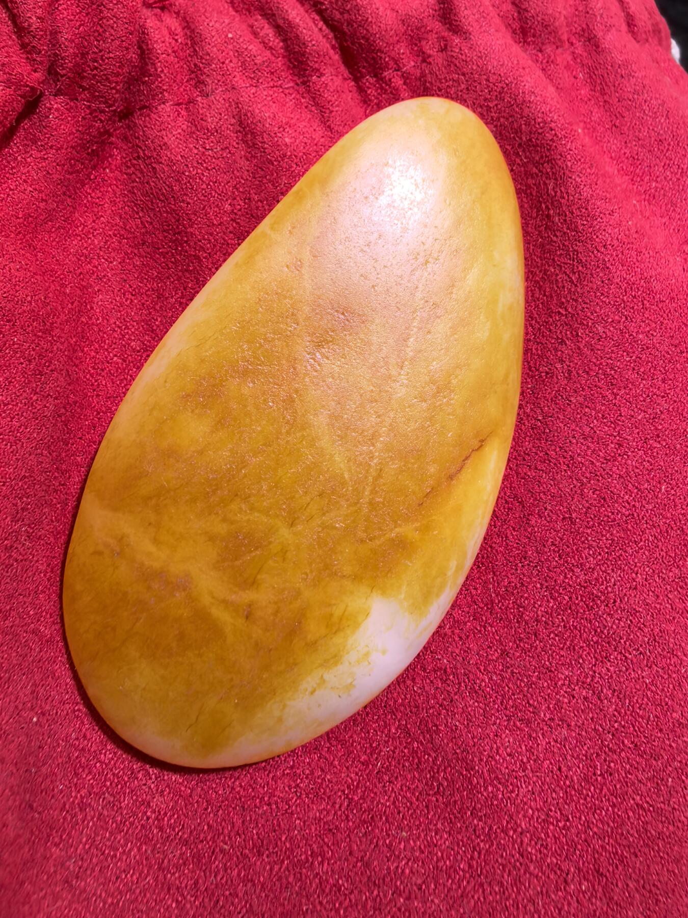 收藏级新疆和田籽料金红皮吊坠挂件手把件男款，原皮、原籽、无修、无烧皮、无做色、通体可见天然毛孔撞击坑等。玉质温润细腻，过灯无明显结构。细度高老熟，暖白不闪青，皮色鲜艳，亮气自然。未打孔。实物实拍，所见即所得。
尺寸:7.5cm*3.9cm*1.3cm
克重:68.5g