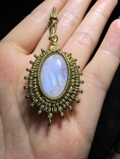 来自委内瑞拉国际友人手工绕丝工艺，月光石吊坠 从不同角度观察，它展现出不同的色彩魅力。有时是极光般的梦幻色彩，有时是少女般的温柔色彩，还有时是落日晚霞般的绚烂色彩。 佩戴与众不同独一无二。 尺寸:2.9cm*2.6cm*1.9cm ​