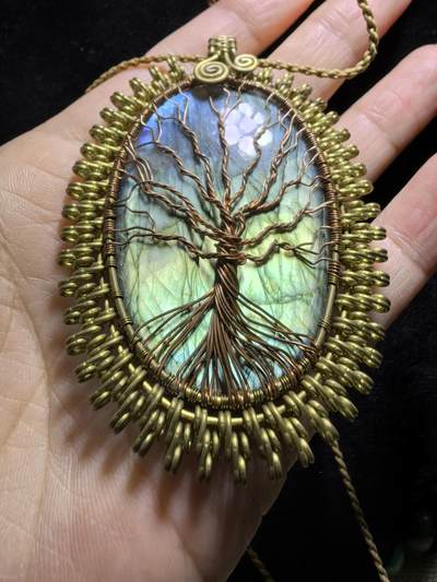 委内瑞拉国际友人纯手工绕丝工艺《灵光生命之树吊坠》男女款
以铜线手工编织的生命之树坐落在蓝火拉布拉多长石之上，整件作品带来更强的净化与守护能量。采用巴西编绳，可自由调节长度。
一件汇聚光、根与灵性的护符。
​尺寸：7.1cm*5.1cm*0.8cm每一款都是独一无二，非量产。
​天然有机宝石内部无法避免结构纹理等，介意勿扰！