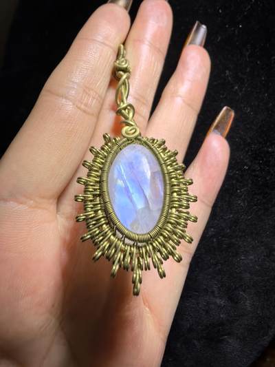 来自委内瑞拉国际友人手工绕丝工艺，月光石吊坠 从不同角度观察，它展现出不同的色彩魅力。有时是极光般的梦幻色彩，有时是少女般的温柔色彩，还有时是落日晚霞般的绚烂色彩。 佩戴与众不同独一无二。 尺寸:2.9cm*2.6cm*1.9cm ​