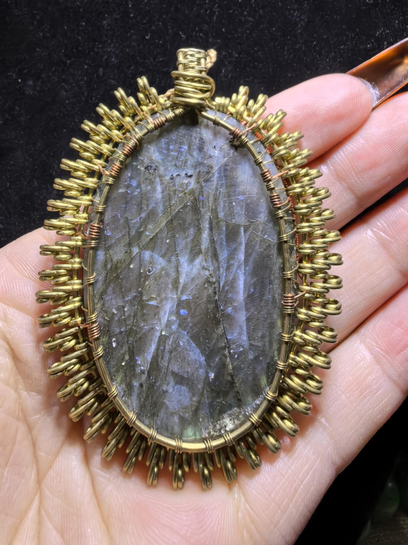 委内瑞拉国际友人纯手工绕丝工艺《灵光生命之树吊坠》男女款
以铜线手工编织的生命之树坐落在蓝火拉布拉多长石之上，整件作品带来更强的净化与守护能量。采用巴西编绳，可自由调节长度。
一件汇聚光、根与灵性的护符。
​尺寸：7.1cm*5.1cm*0.8cm每一款都是独一无二，非量产。
​天然有机宝石内部无法避免结构纹理等，介意勿扰！