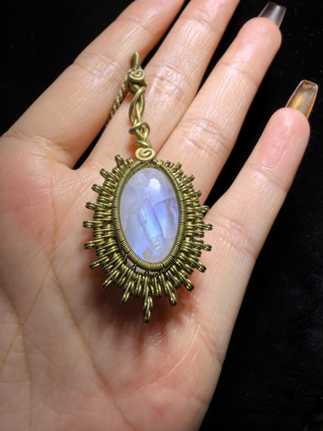 来自委内瑞拉国际友人手工绕丝工艺，月光石吊坠 从不同角度观察，它展现出不同的色彩魅力。有时是极光般的梦幻色彩，有时是少女般的温柔色彩，还有时是落日晚霞般的绚烂色彩。 佩戴与众不同独一无二。 尺寸:2.9cm*2.6cm*1.9cm ​