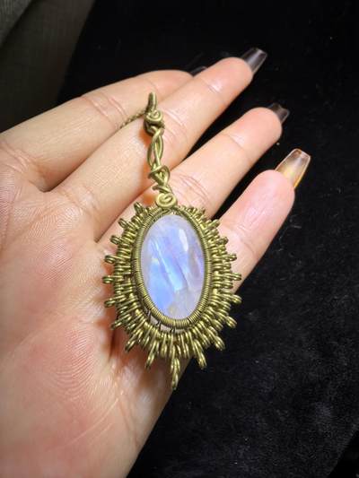 来自委内瑞拉国际友人手工绕丝工艺，月光石吊坠 从不同角度观察，它展现出不同的色彩魅力。有时是极光般的梦幻色彩，有时是少女般的温柔色彩，还有时是落日晚霞般的绚烂色彩。 佩戴与众不同独一无二。 尺寸:2.9cm*2.6cm*1.9cm ​