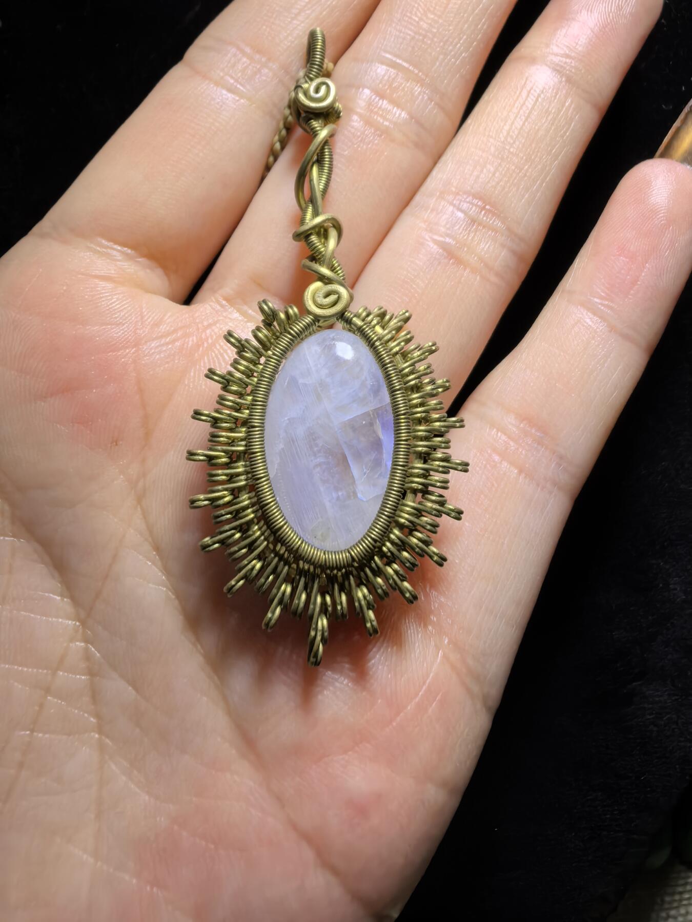 来自委内瑞拉国际友人手工绕丝工艺，月光石吊坠 从不同角度观察，它展现出不同的色彩魅力。有时是极光般的梦幻色彩，有时是少女般的温柔色彩，还有时是落日晚霞般的绚烂色彩。 佩戴与众不同独一无二。 尺寸:2.9cm*2.6cm*1.9cm ​