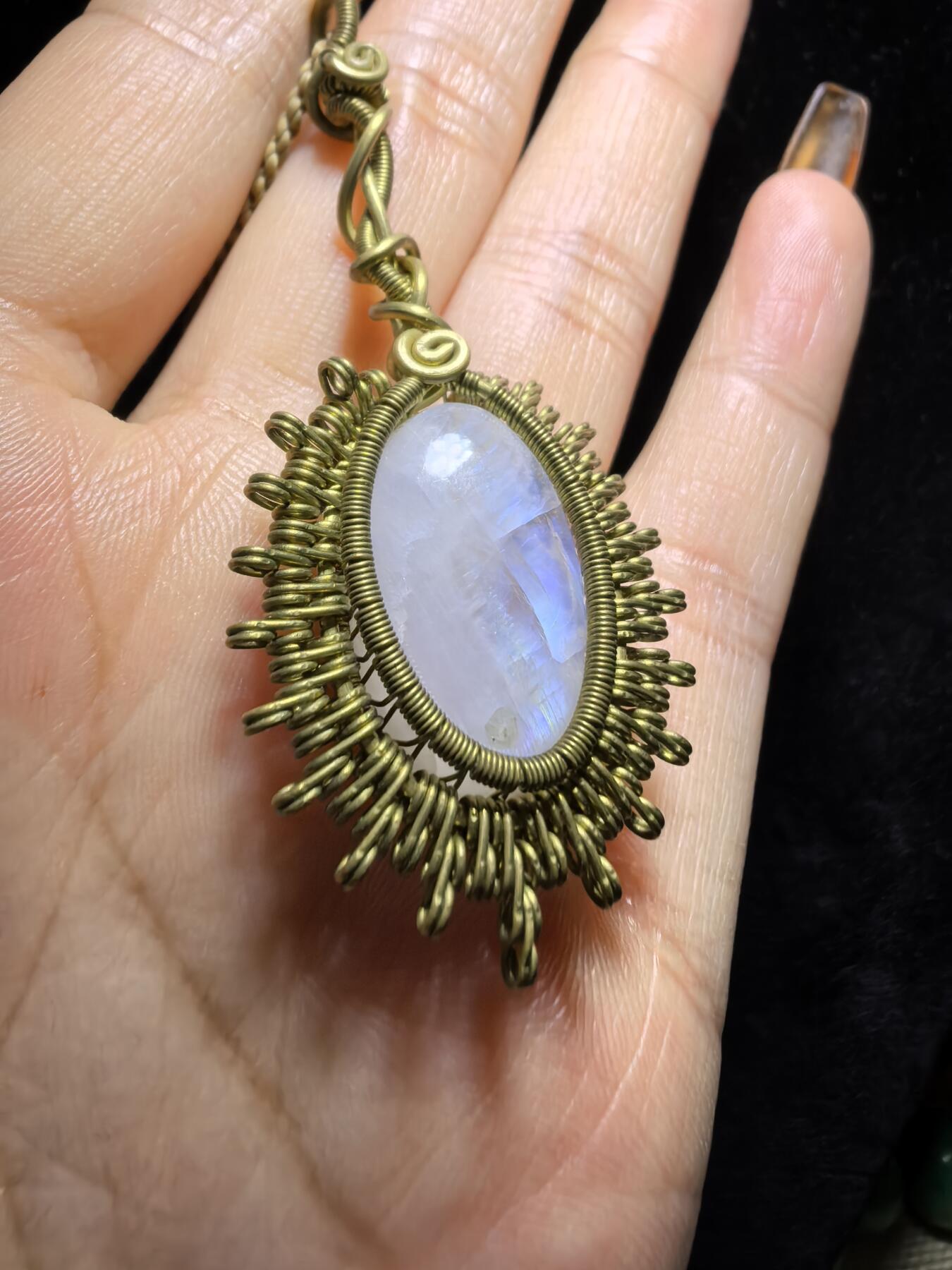 来自委内瑞拉国际友人手工绕丝工艺，月光石吊坠 从不同角度观察，它展现出不同的色彩魅力。有时是极光般的梦幻色彩，有时是少女般的温柔色彩，还有时是落日晚霞般的绚烂色彩。 佩戴与众不同独一无二。 尺寸:2.9cm*2.6cm*1.9cm ​