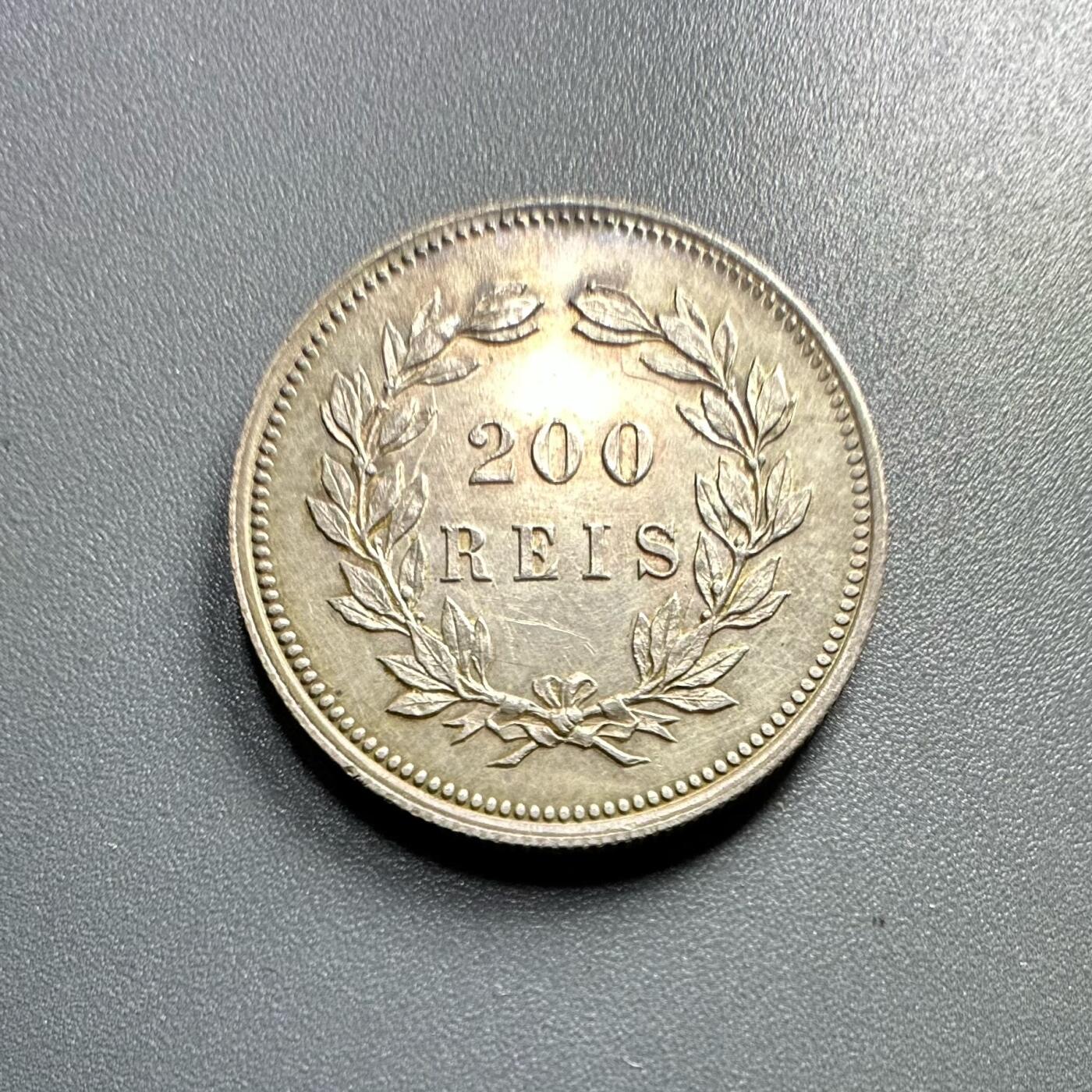 葡萄牙王国1891年200瑞斯的银币
	●	肖像与人物：
币面是卡洛斯一世（Carlos I）的侧面像（葡萄牙国王，1889 - 1908年在位），肖像风格体现19世纪末欧洲王室钱币的写实艺术特征。
	●	铭文与背景：
环绕葡萄牙文“CARLOS I REI DE PORTUGAL”（大意为“卡洛斯一世，葡萄牙国王”），明确君主身份与国家属性；下方“1891” 是铸造年份，“ALVES” 是雕刻师的名字（负责钱币肖像的模具雕刻）。
	●	材质与形制：圆形形制，边缘有珠纹装饰，工艺规整。