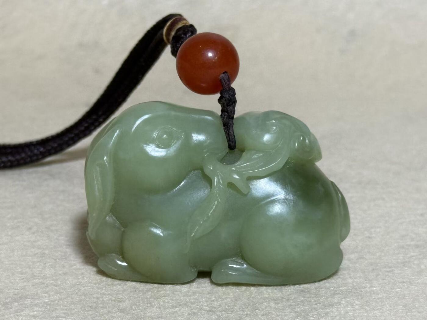 和田玉羊携灵芝手把件
玉质细腻，雕工生动，灵芝造型寓意吉祥
配红玛瑙珠，挂绳完整
成色几乎全新，无明显瑕疵
适合把玩收藏，送礼自用皆宜
无证书，重量约80克