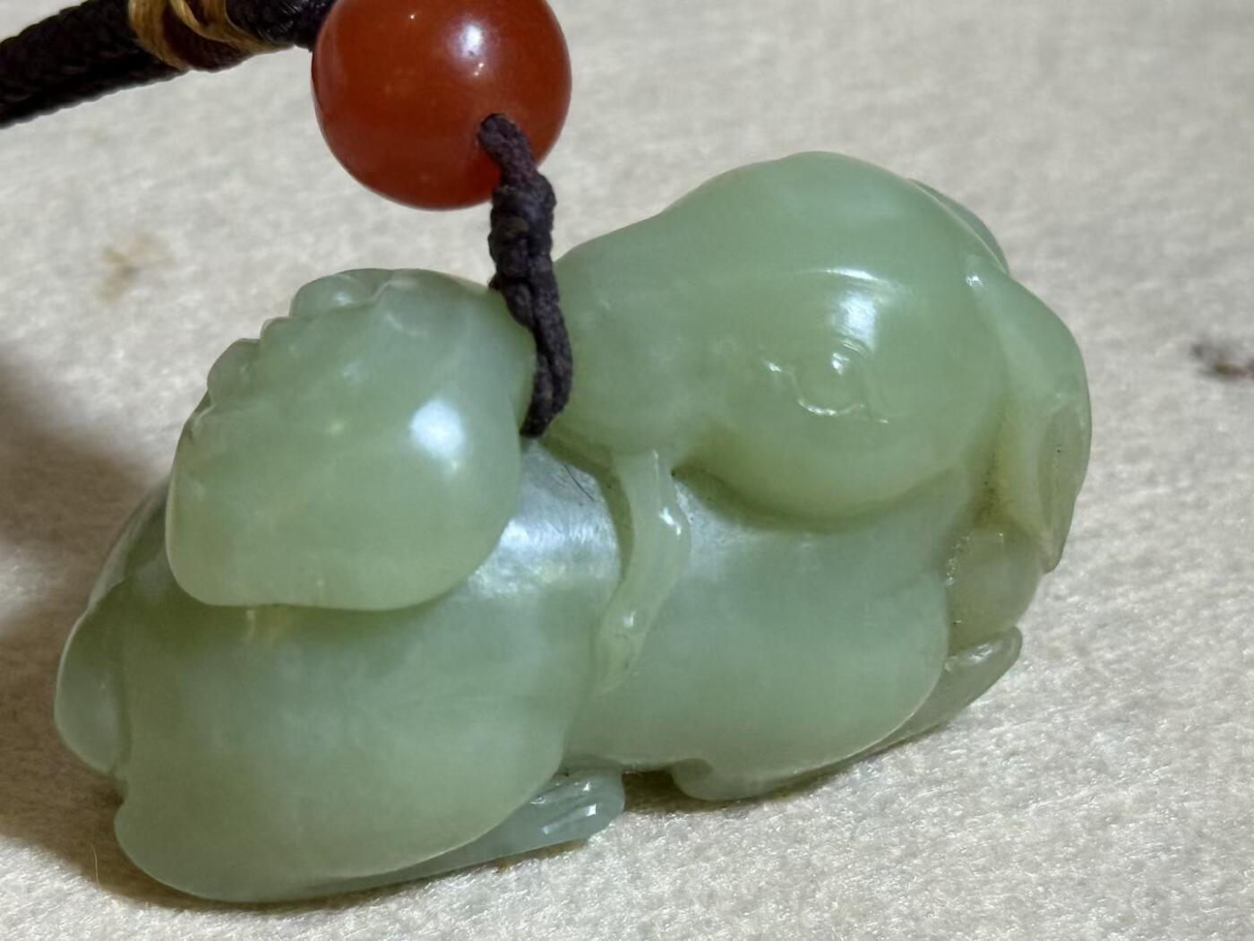 和田玉羊携灵芝手把件
玉质细腻，雕工生动，灵芝造型寓意吉祥
配红玛瑙珠，挂绳完整
成色几乎全新，无明显瑕疵
适合把玩收藏，送礼自用皆宜
无证书，重量约80克