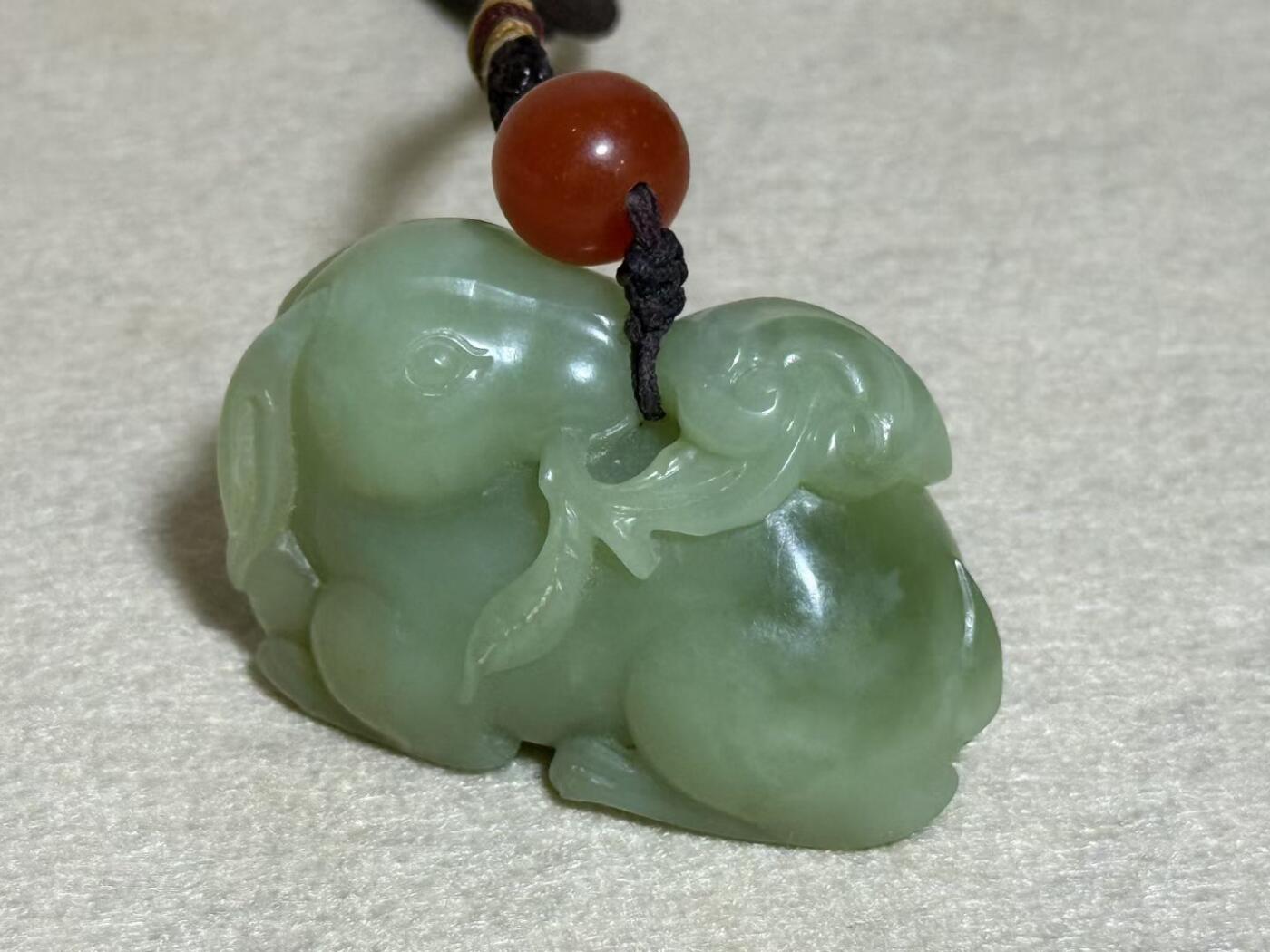 和田玉羊携灵芝手把件
玉质细腻，雕工生动，灵芝造型寓意吉祥
配红玛瑙珠，挂绳完整
成色几乎全新，无明显瑕疵
适合把玩收藏，送礼自用皆宜
无证书，重量约80克