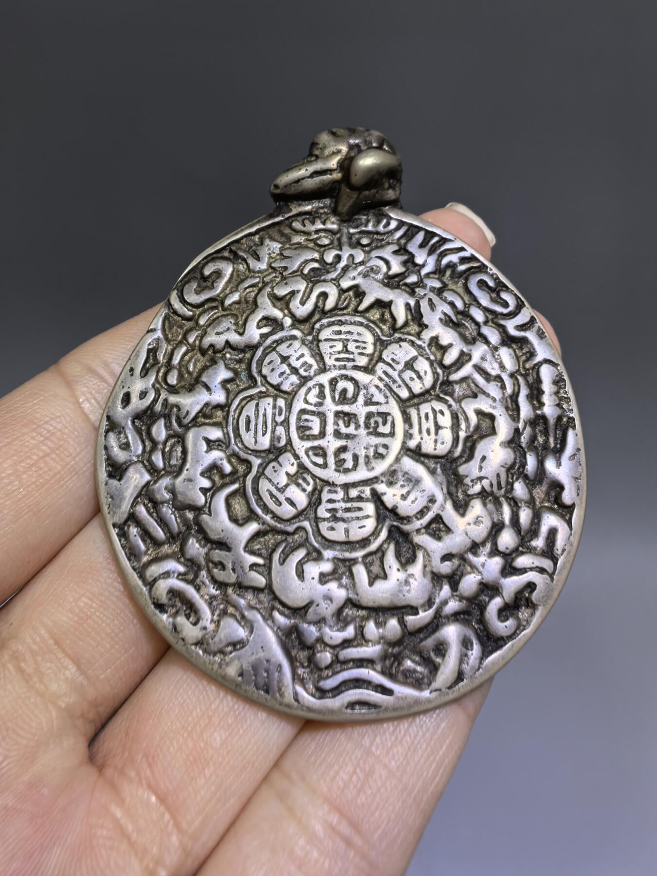 清代藏传九宫八卦牌｜藏地护佑，岁月凝华【清代·藏传九宫八卦护身牌】
材质：铜
工艺：手工铸造、满工高浮雕錾刻
纹饰：中央九宫八卦咒轮，环绕十二生肖、护法神兽、梵文真言
品相：传世美品，包浆醇厚，工艺精湛，保存完好
九宫八卦牌是藏传佛教中最具影响力的护身法器之一此牌为清代传世之物，工艺精湛，文化价值极高。6.6cm*5.48cm*0.3cm克重：52.1g