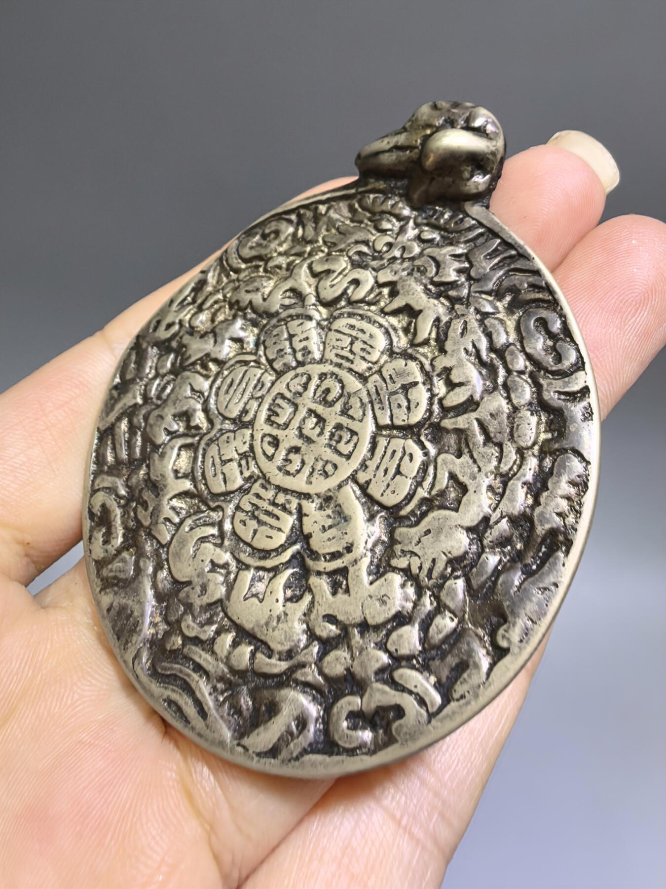 清代藏传九宫八卦牌｜藏地护佑，岁月凝华【清代·藏传九宫八卦护身牌】
材质：铜
工艺：手工铸造、满工高浮雕錾刻
纹饰：中央九宫八卦咒轮，环绕十二生肖、护法神兽、梵文真言
品相：传世美品，包浆醇厚，工艺精湛，保存完好
九宫八卦牌是藏传佛教中最具影响力的护身法器之一此牌为清代传世之物，工艺精湛，文化价值极高。6.6cm*5.48cm*0.3cm克重：52.1g