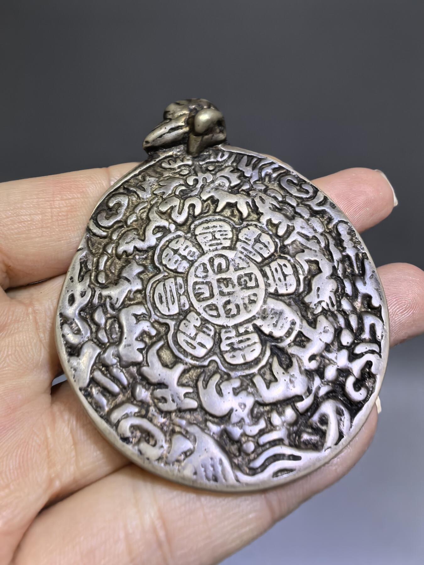 清代藏传九宫八卦牌｜藏地护佑，岁月凝华【清代·藏传九宫八卦护身牌】
材质：铜
工艺：手工铸造、满工高浮雕錾刻
纹饰：中央九宫八卦咒轮，环绕十二生肖、护法神兽、梵文真言
品相：传世美品，包浆醇厚，工艺精湛，保存完好
九宫八卦牌是藏传佛教中最具影响力的护身法器之一此牌为清代传世之物，工艺精湛，文化价值极高。6.6cm*5.48cm*0.3cm克重：52.1g