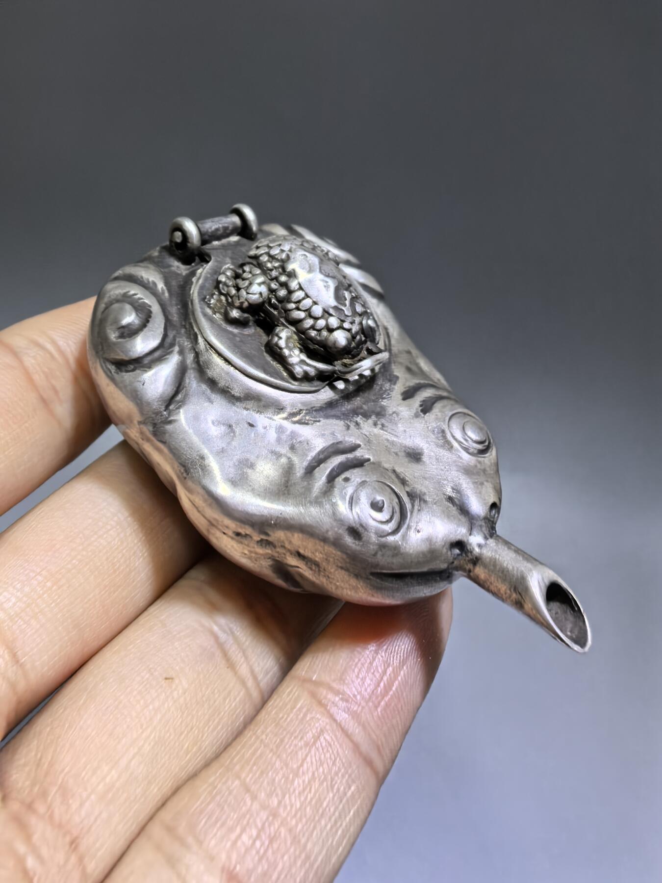 老银金蟾砚滴案头纳福墨韵生清代·老银金蟾纹砚滴材质：足银工艺：手工锻打、高浮雕錾刻器型：随形砚滴，云纹为底，金蟾为钮，壶嘴精巧品相：传世美品，包浆醇厚，工艺精湛金蟾为传统招财瑞兽，此砚滴以银为材，将瑞兽与文房雅器结合，既具实用价值，又含吉祥寓意，是清代银制文房的精品之作极具收藏与赏玩价值​6.3cm*4.0cm*2.8cm克重：24g#砚滴#清代#老银