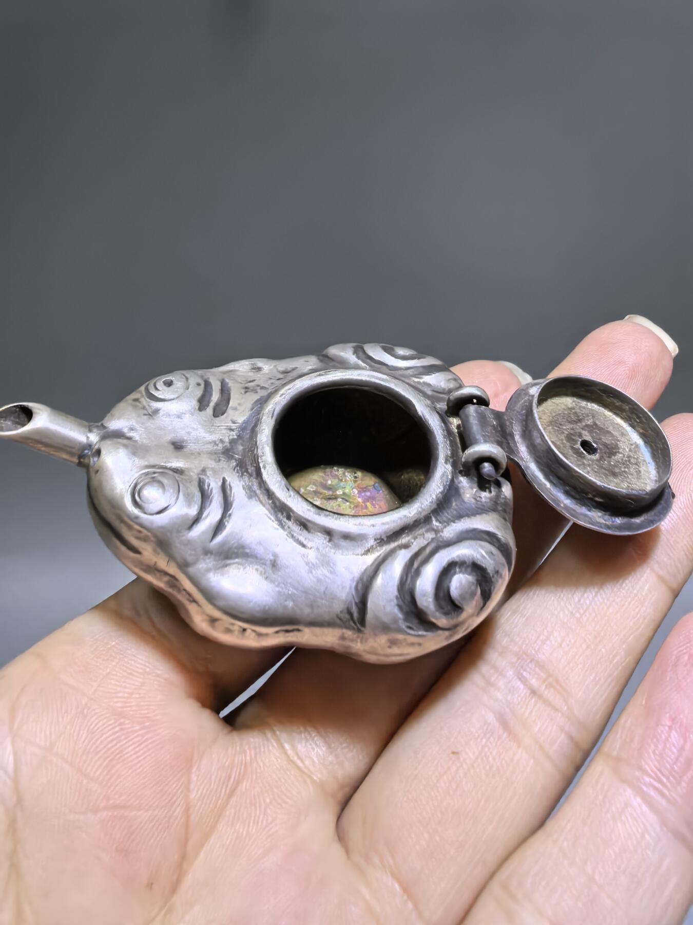 老银金蟾砚滴案头纳福墨韵生清代·老银金蟾纹砚滴材质：足银工艺：手工锻打、高浮雕錾刻器型：随形砚滴，云纹为底，金蟾为钮，壶嘴精巧品相：传世美品，包浆醇厚，工艺精湛金蟾为传统招财瑞兽，此砚滴以银为材，将瑞兽与文房雅器结合，既具实用价值，又含吉祥寓意，是清代银制文房的精品之作极具收藏与赏玩价值​6.3cm*4.0cm*2.8cm克重：24g#砚滴#清代#老银