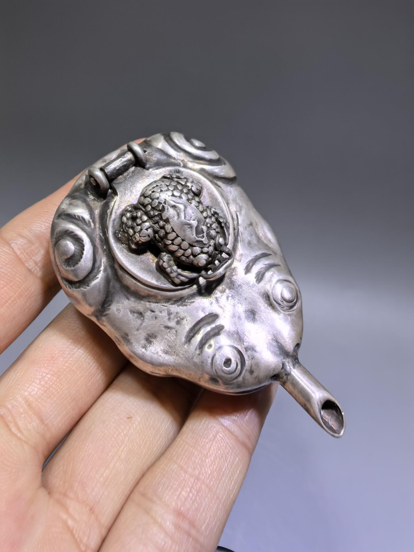 老银金蟾砚滴案头纳福墨韵生清代·老银金蟾纹砚滴材质：足银工艺：手工锻打、高浮雕錾刻器型：随形砚滴，云纹为底，金蟾为钮，壶嘴精巧品相：传世美品，包浆醇厚，工艺精湛金蟾为传统招财瑞兽，此砚滴以银为材，将瑞兽与文房雅器结合，既具实用价值，又含吉祥寓意，是清代银制文房的精品之作极具收藏与赏玩价值​6.3cm*4.0cm*2.8cm克重：24g#砚滴#清代#老银