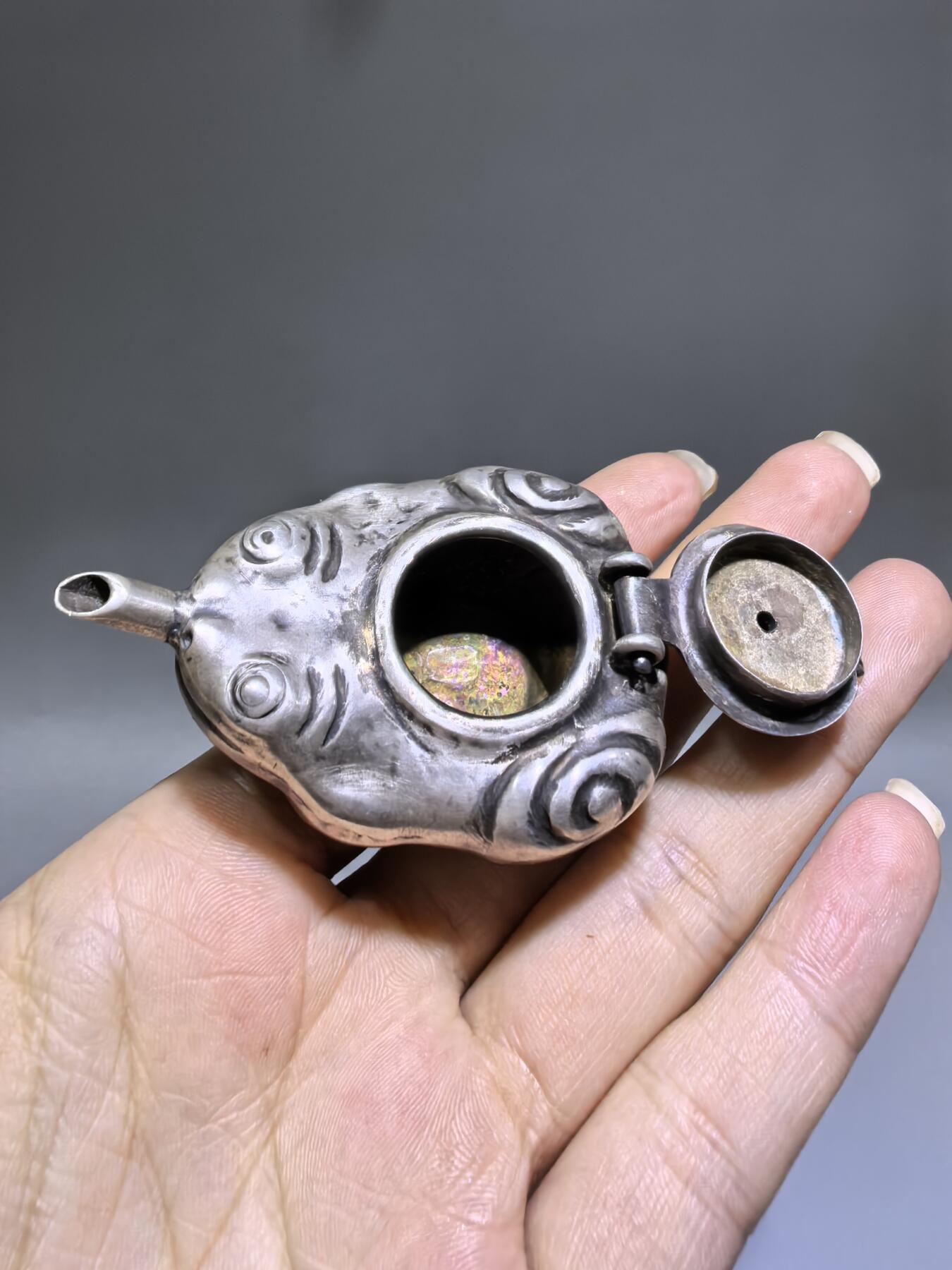 老银金蟾砚滴案头纳福墨韵生清代·老银金蟾纹砚滴材质：足银工艺：手工锻打、高浮雕錾刻器型：随形砚滴，云纹为底，金蟾为钮，壶嘴精巧品相：传世美品，包浆醇厚，工艺精湛金蟾为传统招财瑞兽，此砚滴以银为材，将瑞兽与文房雅器结合，既具实用价值，又含吉祥寓意，是清代银制文房的精品之作极具收藏与赏玩价值​6.3cm*4.0cm*2.8cm克重：24g#砚滴#清代#老银