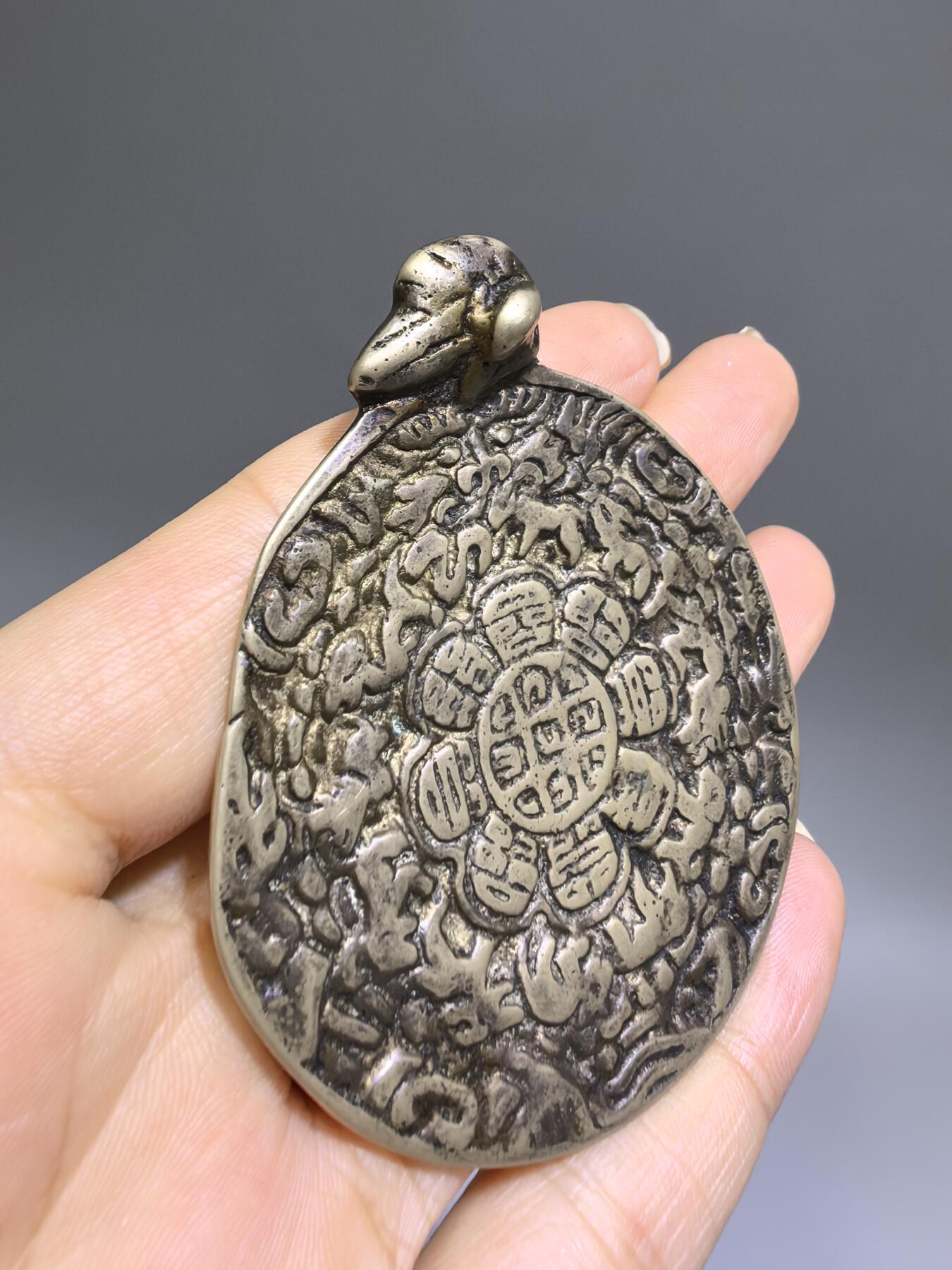 清代藏传九宫八卦牌｜藏地护佑，岁月凝华【清代·藏传九宫八卦护身牌】
材质：铜
工艺：手工铸造、满工高浮雕錾刻
纹饰：中央九宫八卦咒轮，环绕十二生肖、护法神兽、梵文真言
品相：传世美品，包浆醇厚，工艺精湛，保存完好
九宫八卦牌是藏传佛教中最具影响力的护身法器之一此牌为清代传世之物，工艺精湛，文化价值极高。6.6cm*5.48cm*0.3cm克重：52.1g