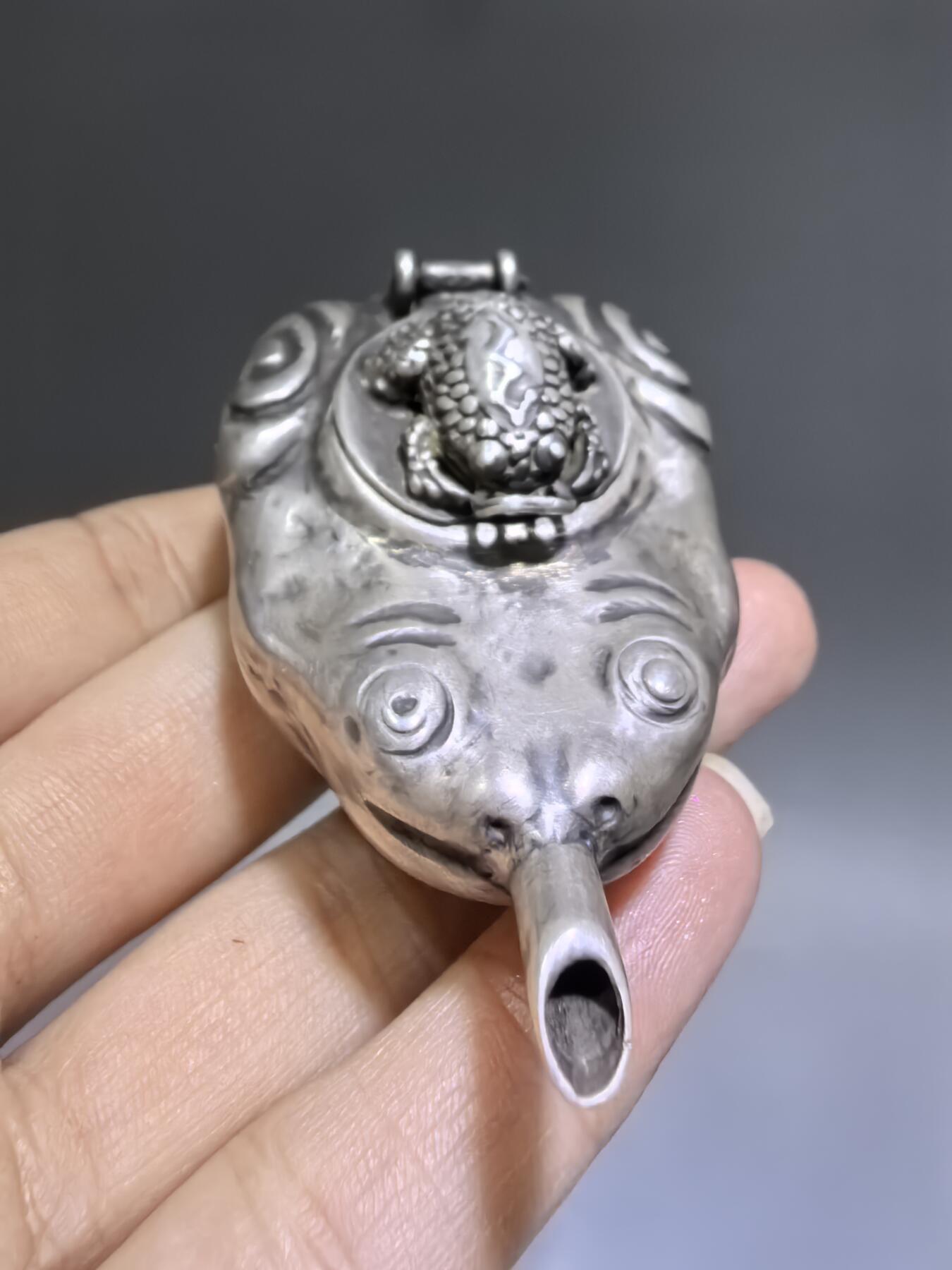 老银金蟾砚滴案头纳福墨韵生清代·老银金蟾纹砚滴材质：足银工艺：手工锻打、高浮雕錾刻器型：随形砚滴，云纹为底，金蟾为钮，壶嘴精巧品相：传世美品，包浆醇厚，工艺精湛金蟾为传统招财瑞兽，此砚滴以银为材，将瑞兽与文房雅器结合，既具实用价值，又含吉祥寓意，是清代银制文房的精品之作极具收藏与赏玩价值​6.3cm*4.0cm*2.8cm克重：24g#砚滴#清代#老银