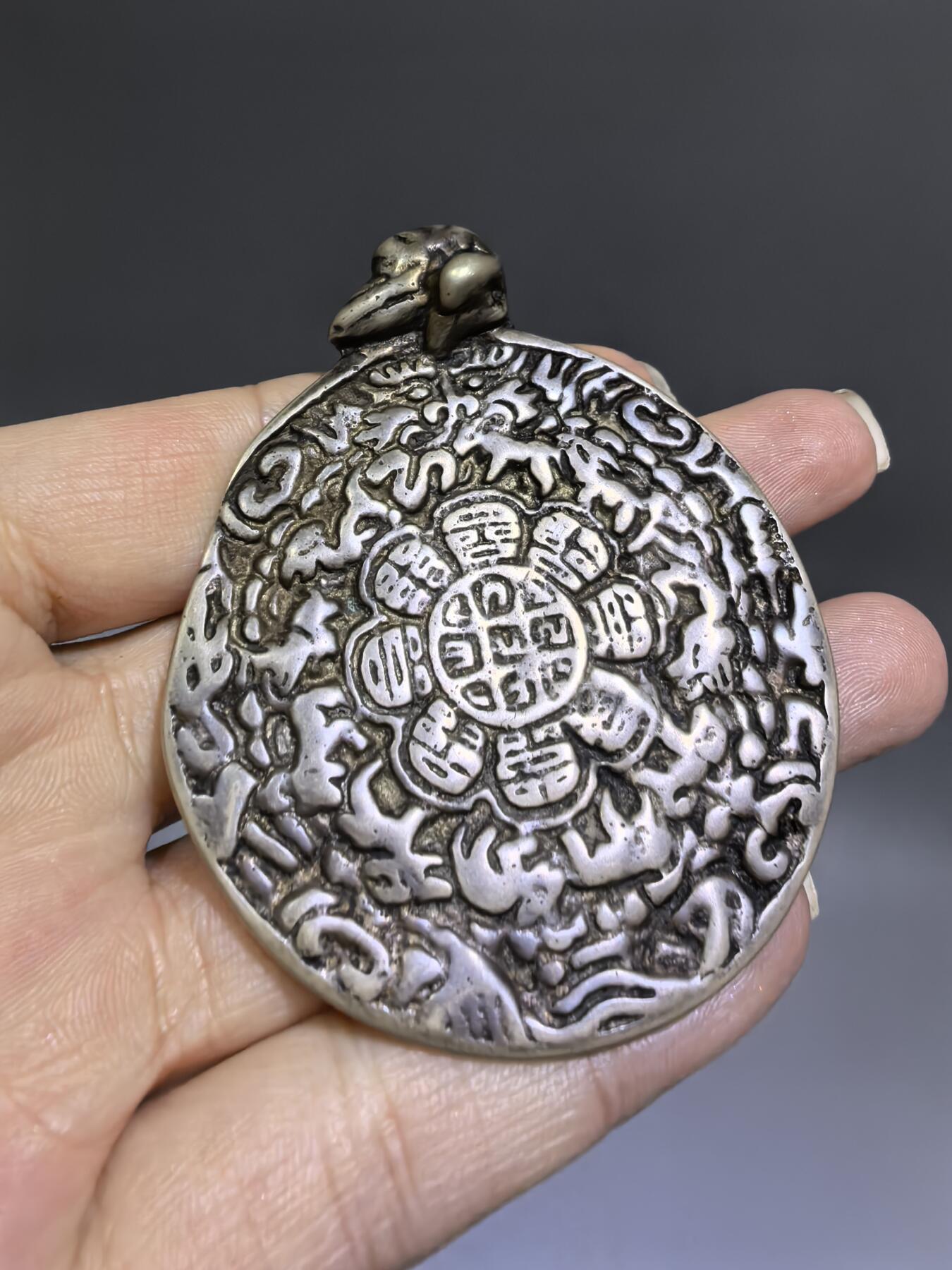 清代藏传九宫八卦牌｜藏地护佑，岁月凝华【清代·藏传九宫八卦护身牌】
材质：铜
工艺：手工铸造、满工高浮雕錾刻
纹饰：中央九宫八卦咒轮，环绕十二生肖、护法神兽、梵文真言
品相：传世美品，包浆醇厚，工艺精湛，保存完好
九宫八卦牌是藏传佛教中最具影响力的护身法器之一此牌为清代传世之物，工艺精湛，文化价值极高。6.6cm*5.48cm*0.3cm克重：52.1g