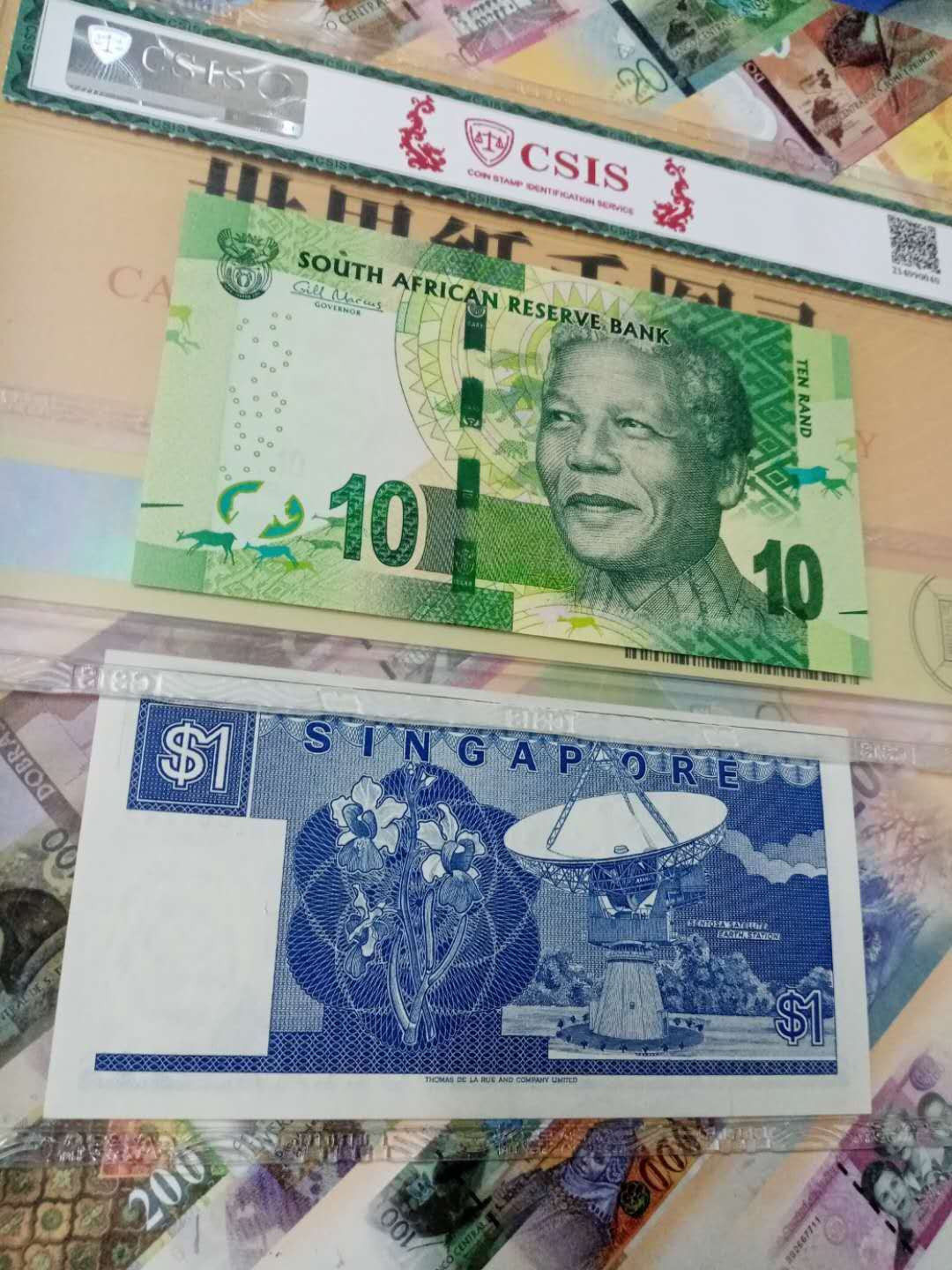 【鲸贝乐淘】千字文·第“背邙面洛，浮渭据泾”号拍卖 【南非🇿🇦 ·新加坡🇸🇬 】2012年10兰特，信泰66E，1987年船版1元，美评65E