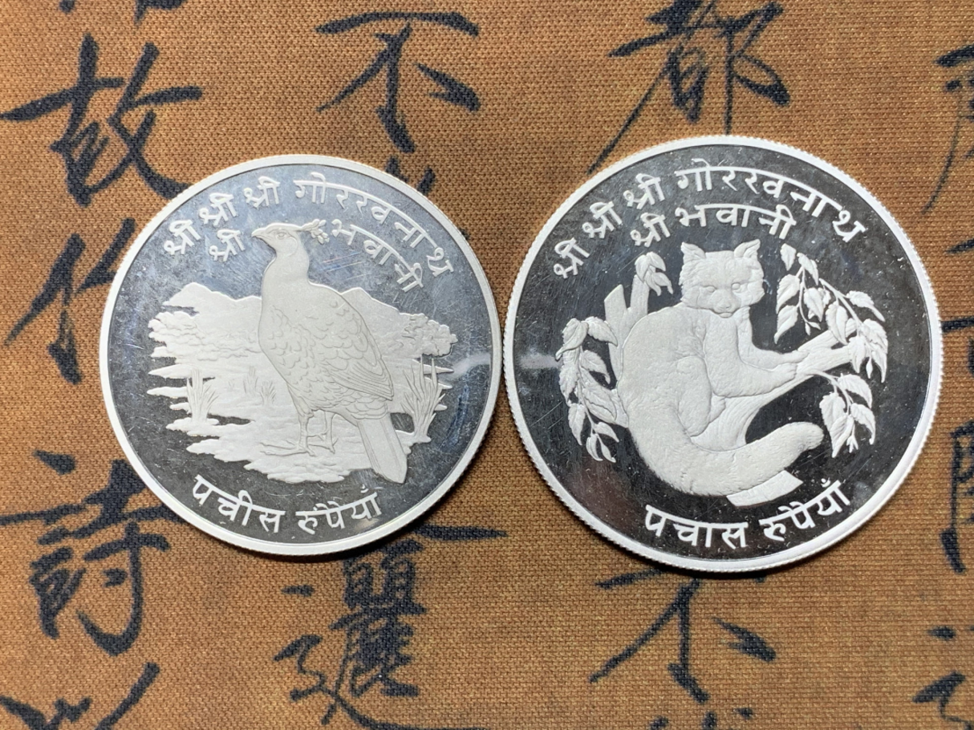 《竞宝斋》钱币微拍-第23场（全场顺丰包邮） 尼泊尔1974年25卢比、50卢比精制大银币一对 925银，重量分别为28.28g、35g，直径分别为38.61mm、42mm，发行量1万1千枚/1万枚。图案主题：珍稀动物野鸡/珍稀动物红熊猫。